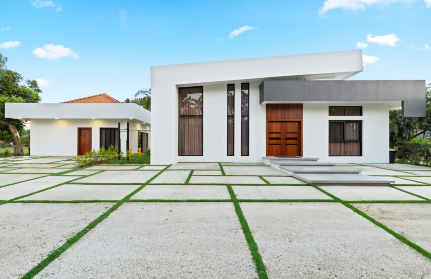 A contemporary white house facade with front garden and entrance featuring concrete tiles
